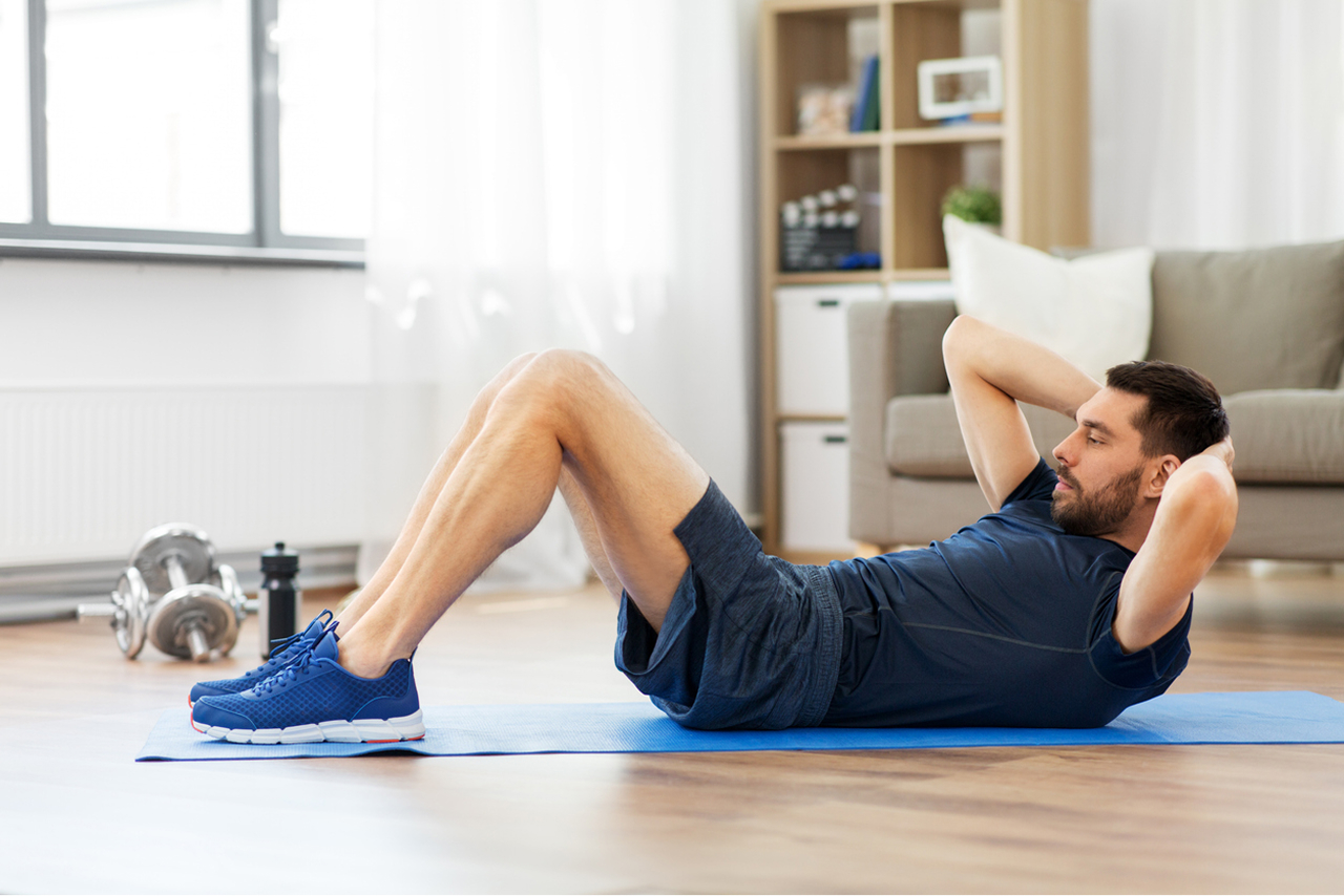 Person exercising at home with a yoga mat and dumbbells